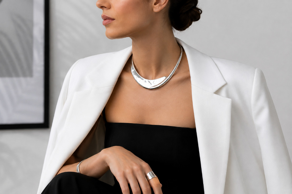 Collier statement argenté associé à une tenue noire et blanche pour un look moderne et minimaliste.