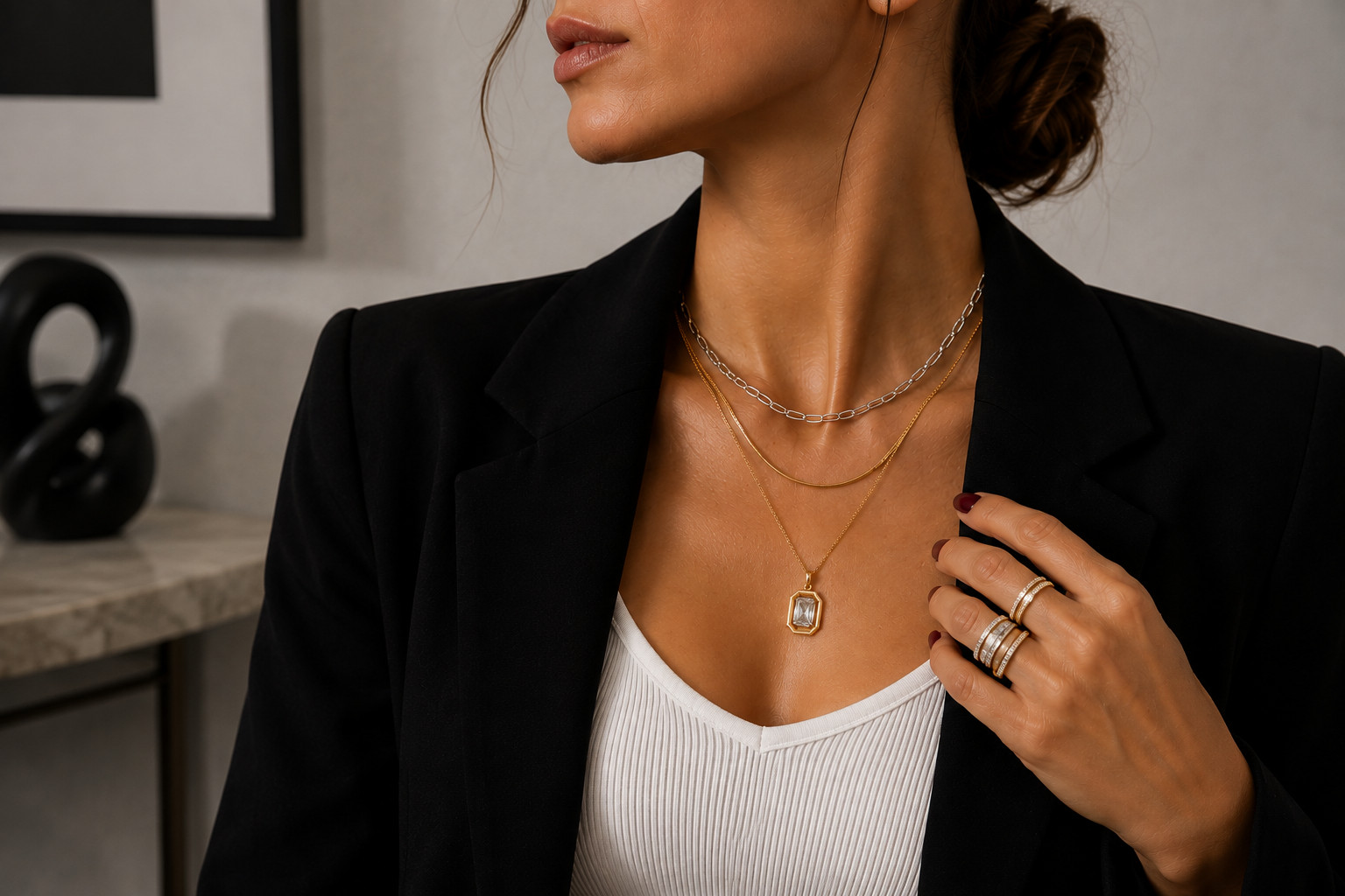 Colliers dorés et argentés superposés avec une tenue noire et blanche pour un look mixed metals moderne.